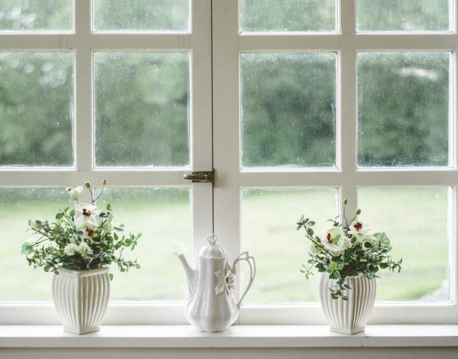 white teapot and tow flower vases on windowpane